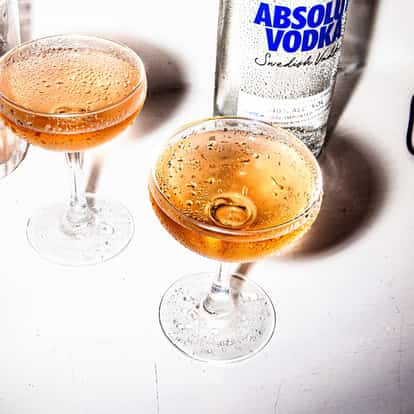 Quattro Bianchi served in two coupe glasses with an Absolut vodka bottle on white background.