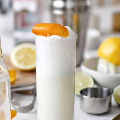 Ramos Gin Fizz served in a Collins glass with foamy head and orange peel garnish