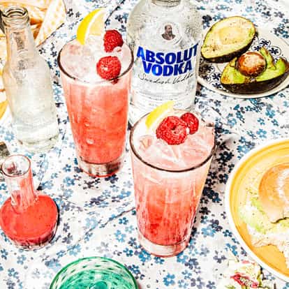 Raspberry Fields Forever cocktail in a festive atmosphere next to a bottle of Absolut Vodka.