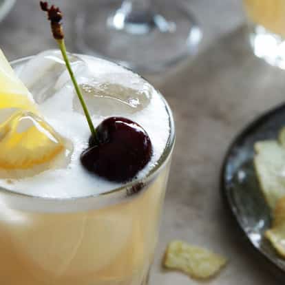 Rum sour garnished with a lemon wedge and maraschino cherry