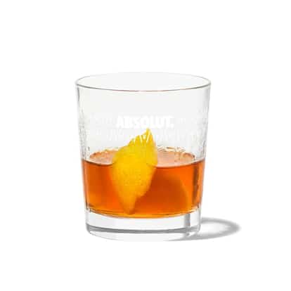 Sazerac served in an Absolut rocks glass with lemon peel on white background