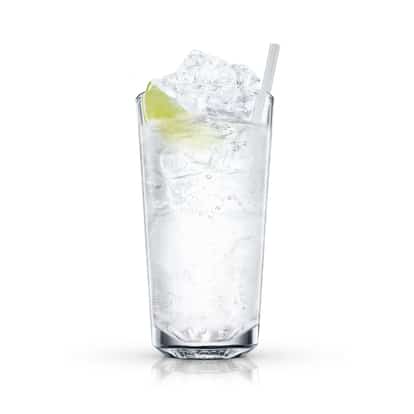 A tall highball glass holds a clear drink, crushed ice, a lime wedge and a straw on white background.