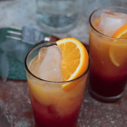 Two So Sunrise served in tall glasses with ice and orange wedges.