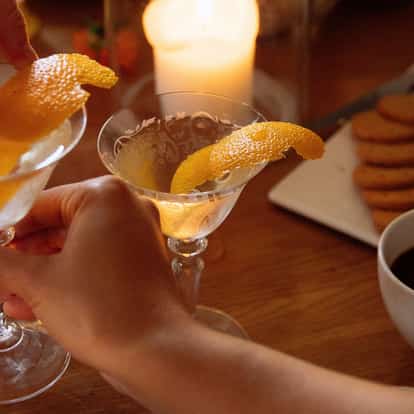 Soho Martini garnished with a fresh orange twist next to a cup of black coffee.