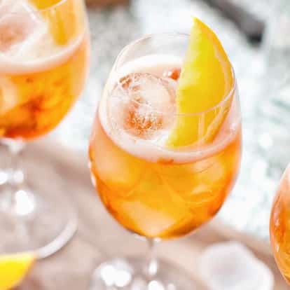 Spritz Veneziano served in stemmed wine glasses with ice and orange slices