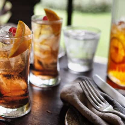 Summer Iced Tea cocktails next to glassware and a pitcher.