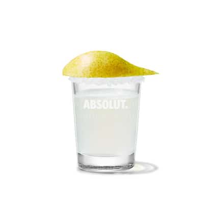 Cocktail in an Absolut rocks glass with a pear slice garnish on white background.