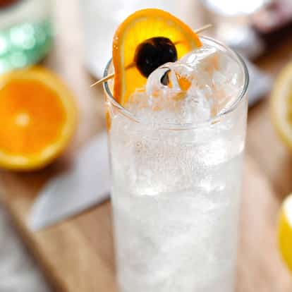 Tom Collins in a tall Collins glass garnished with an orange slice and cherry.