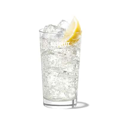 Twisted Tonic in an Absolut highball glass with ice and a lemon wedge on white background