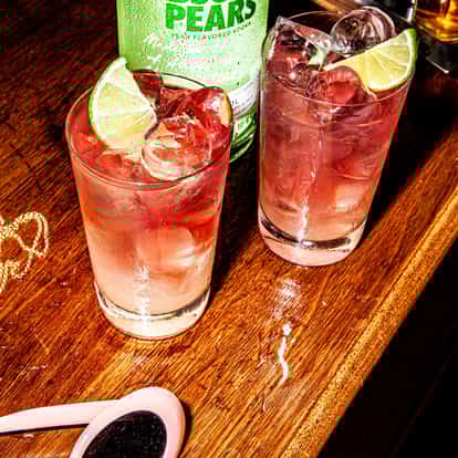 Pear Vodka Breeze on a wooden table next to a bottle of Absolut Pears.