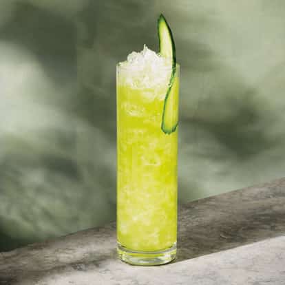 Water On The Vine served in a highball glass with crushed ice and cucumber ribbon garnish on a stone surface