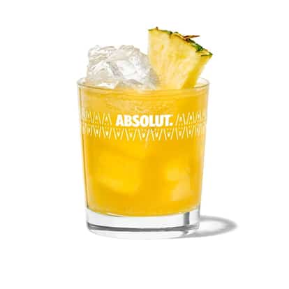 West Indian Cooler in an Absolut rocks glass with ice and pineapple wedge on white background