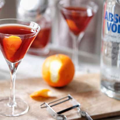 Yankee-dutch in a stemmed martini glass with orange twist and Absolut Vodka bottle on a wooden board