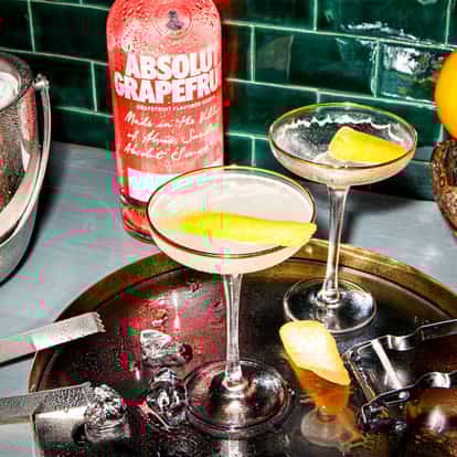 Yin And Yang in two coupe glasses with lemon twists and an Absolut Grapefruit bottle behind