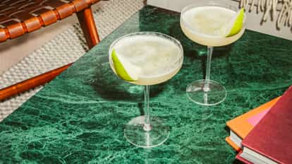 Elderflower Pear Martinis in coupe glasses garnished with fresh pear slices on a green marble table.