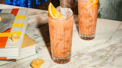 Cóctel Madras en vasos altos texturizados con hielo y gajo de naranja, bebida rosada cítrica sobre mesa de mármol.