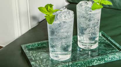 Malibu St Lawrence Lemonade in zwei hohen Gläsern mit Crushed Ice und Minze, serviert auf einem grünen Marmortablett.