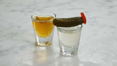 Two shots representing the Pickleback, one with Jameson irish Whiskey, the other with pickle juice.