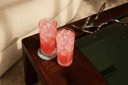 Two Pink Lemonade cocktails on a wooden table.