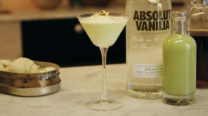 Pistachio Martini next to a bottle of Absolut Vanilia and pistachio cream liqueur.