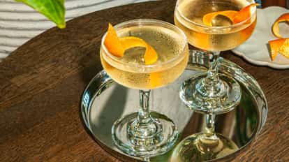 Soho Martini cocktails in chilled coupe glasses with citrus twists, served on a reflective silver tray set on a wooden table.