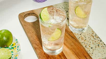 Cócteles de Vodka con Ginger Ale servidos en vasos altos y fríos con hielo y rodajas de lima fresca, colocados sobre una tabla de madera.