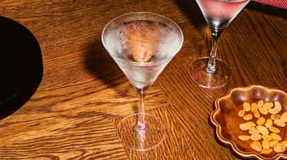 Vodka-Stinger-Cocktails in gekühlten Martinigläsern mit frostigem Schimmer, serviert auf einem Holztisch neben einer kleinen Schale Snacks.