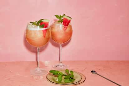 Two Watermelon Cosmopolitan cocktails made with Absolut Watermelon set against a pink background.
