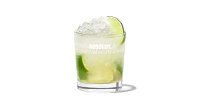 Caipiroska slim fit in an Absolut rocks glass with crushed ice and lime wedges on white background