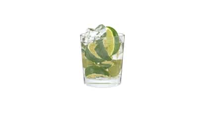 Caipiruva in a rocks glass with ice and lime wedges on white background