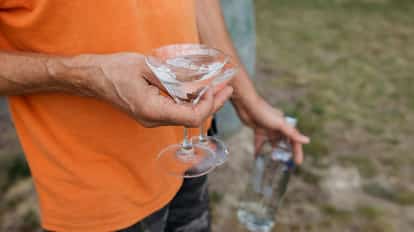 A man from the neck down in an orange t-shirt holds a Chocolate Martini in a coupe glass.