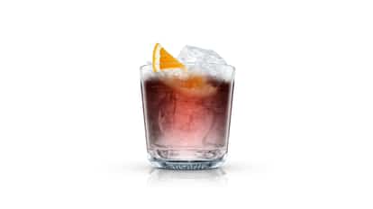 Citron Nigroni in an Absolut rocks glass with large ice cubes and an orange wedge on white background