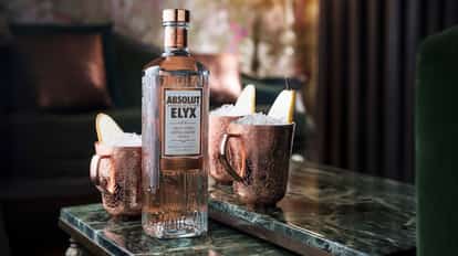 Conference Call with Absolut Elyx bottle and two embossed mule mugs with crushed ice and pear slices on a marble table