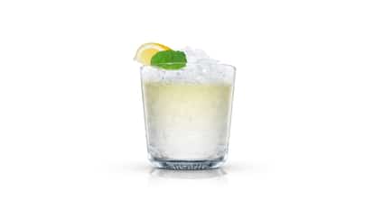 Crushed-ice lemon cocktail with mint in an Absolut rocks glass on white background