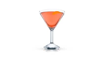 A single coral cocktail in a martini glass with a citrus twist on white background.