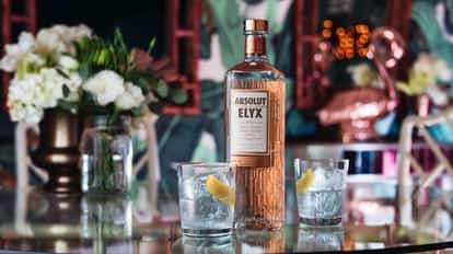 Elyx On The Rock with an Absolut Elyx bottle and two rocks glasses with ice and lemon peel on a mirrored bar surface