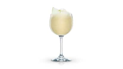 Frozen Apple served in a stemmed wine glass with crushed ice and apple wedge garnish on white background