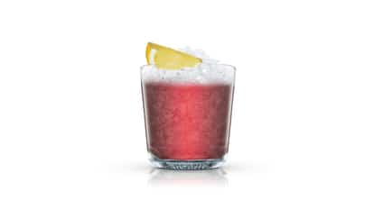 Frozen Blackberry Tequila in an Absolut rocks glass with crushed ice and a lemon wedge on white background