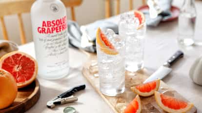 Grapefruit Vodka Soda in a highball glass with ice and a grapefruit wedge, Absolut Grapefruit bottle in background