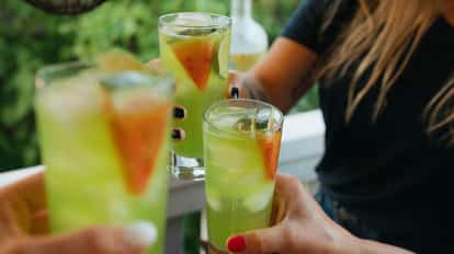 Green Peace in three tall highball glasses with ice and fruit wedge garnishes