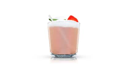 Highland Fresh in an Absolut rocks glass topped with foam and a mint leaf and a strawberry slice on white background