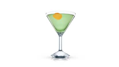 Libertini served in a martini glass with pale green liquid and an orange peel on white background.