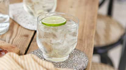 Lime Vodka Tonic on a wooden table in a rock glass garnished with a lime wheel.