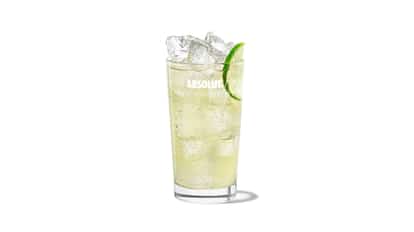 Loretto Lemonade in an Absolut highball glass with ice and a lime wedge on white background