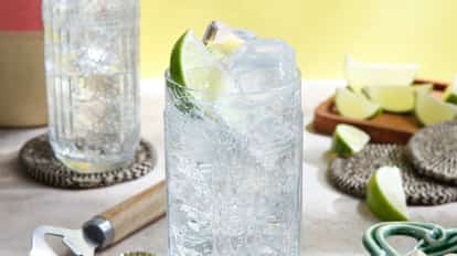 Malibu And Lemon-lime Soda in a highball glass with ice and a lime wedge on a tabletop