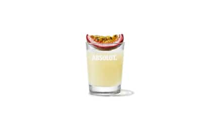 Mandrin & Passion Shot in an Absolut shot glass with a halved passionfruit on the rim