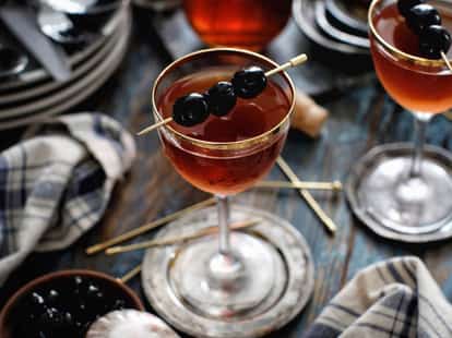 Beautifully composed image of two classic Manhattan cocktails, garnished with three Maraschino Cherries