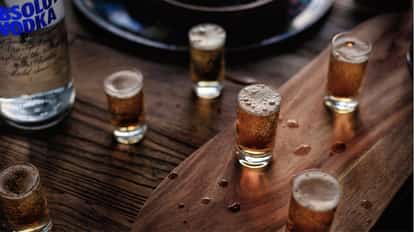 Mind Eraser Shot in several shot glasses on a wooden board with an Absolut Vodka bottle at left