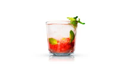 Mojito Raspberry in an Absolut rocks glass with crushed raspberries and a mint sprig on white background
