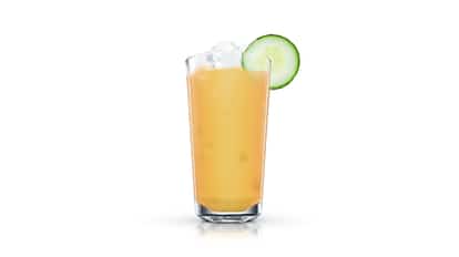Creamy orange drink in a tall highball glass with ice and a cucumber slice on white background.